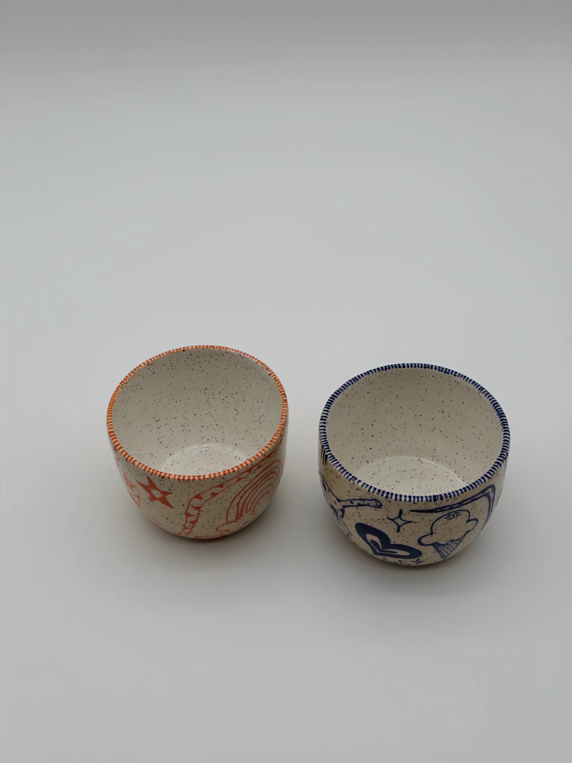 Two cream cups decorated with red and blue doodles