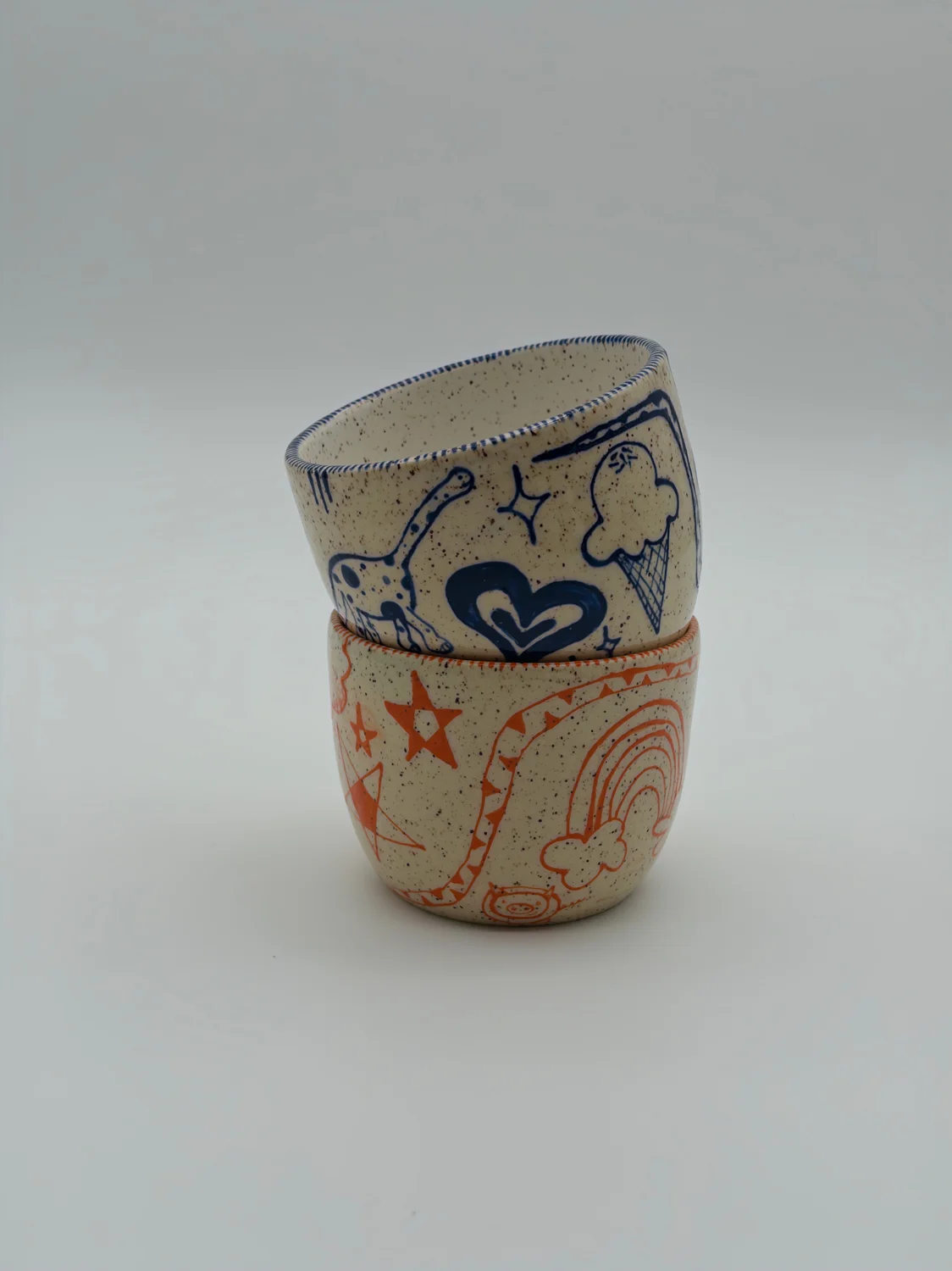 Two cream cups decorated with red and blue doodles, view 2