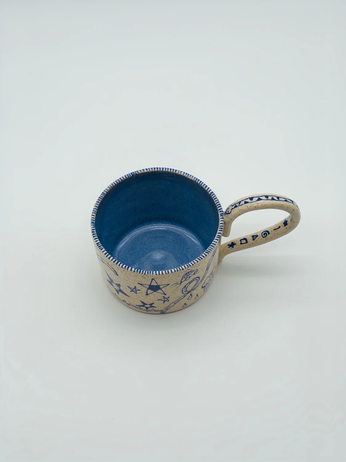 Cream mug with blue doodles, a blue interior, and a curved handle, view 4