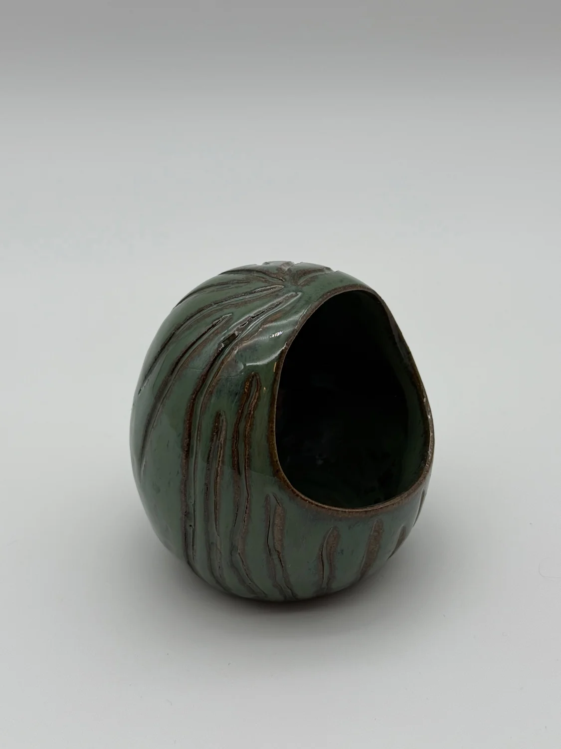 Green glazed salt dish with a rounded opening and carved lines