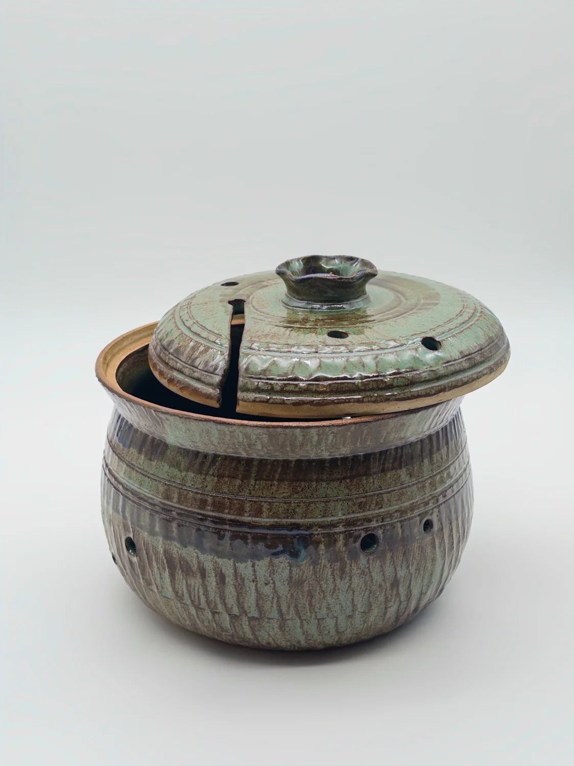 Brown and green lidded pot with small holes and a notch in the lid, view 2